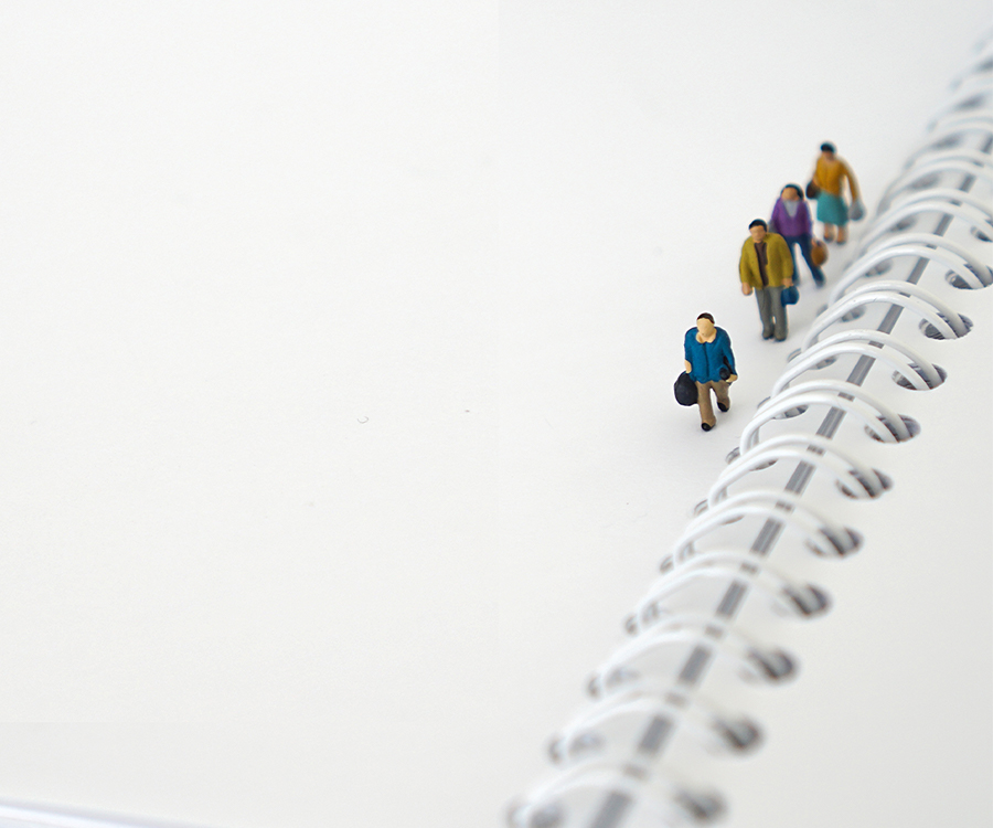 Miniaturfiguren gehen auf Schreibblock